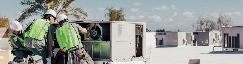 Three Rainforest technicians carefully install a roof top commercial air conditioner. Showcasing the company's dedication to quality workmanship.