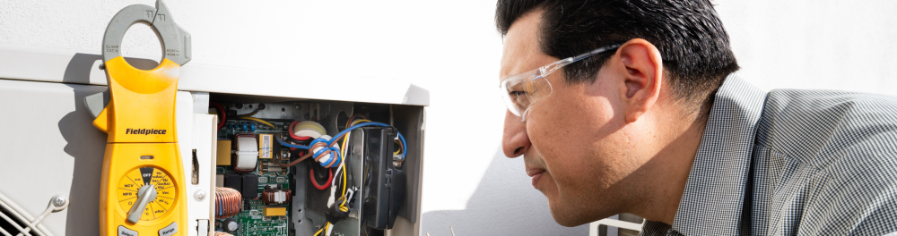 Rainforest Plumbing & Air technician installing a heat pump unit outdoors.