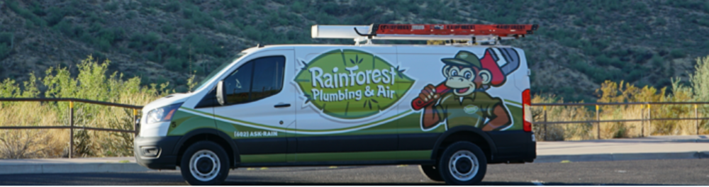 A Rainforest Plumbing & Air branded van parked in the Arizona desert.